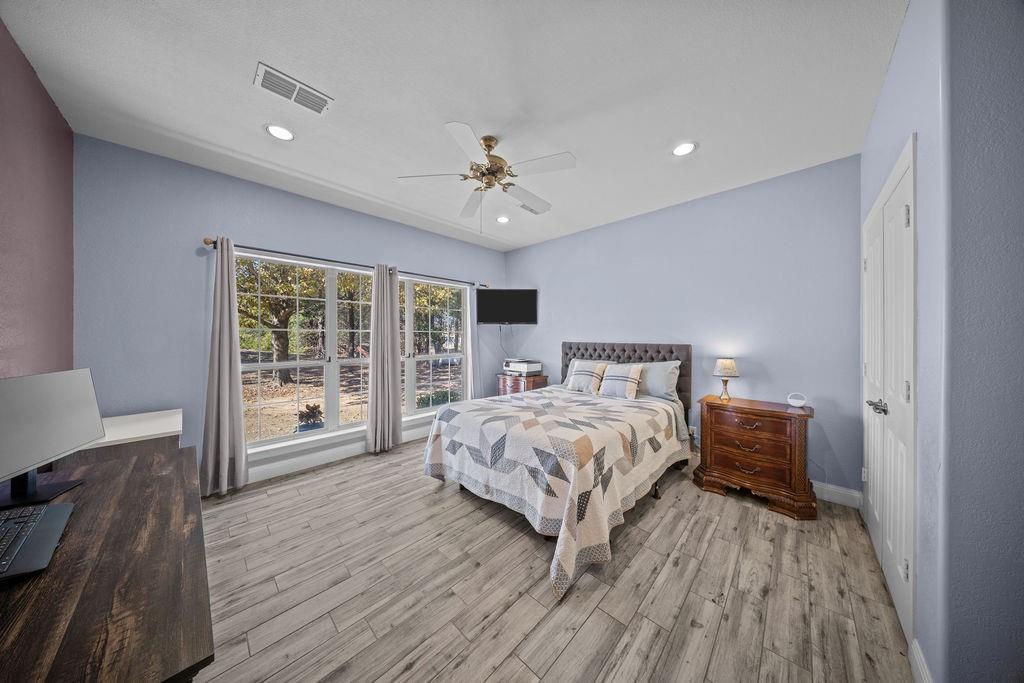 831 Union Hill Road Ennis, TX 75119 - Photo 22 of 38 a spacious bedroom with a large bed and a chandelier