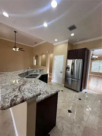 a kitchen with stainless steel appliances kitchen island granite countertop a sink and a refrigerator