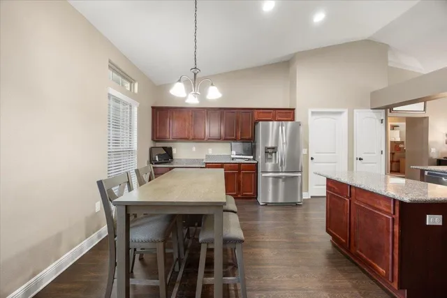 a kitchen with stainless steel appliances a table chairs refrigerator and cabinets