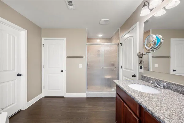 a bathroom with a granite countertop sink a mirror and a shower