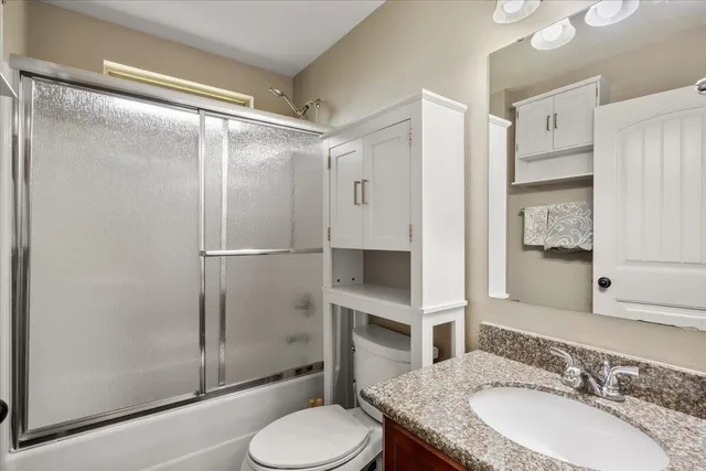 a bathroom with a granite countertop sink toilet and shower