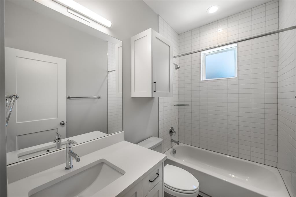 2821 Castro Street, Unit 1 Austin, TX 78702 - Photo 18 of 21 Bathroom featuring a white vanity with an integrated sink and chrome fixtures, subway tile shower surround, a built-in shower niche, and a frosted window