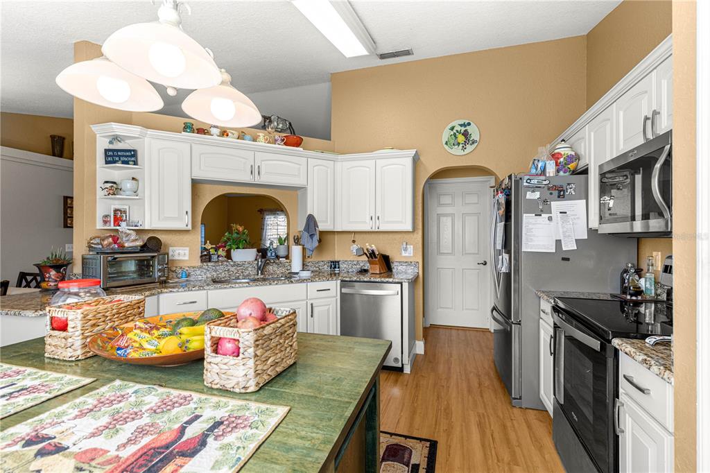 12459 Southeast 176th Loop Summerfield, FL 34491 - Photo 12 of 34 a very nice looking kitchen with granite countertop a stove a sink dishwasher and a fireplace with wooden floor