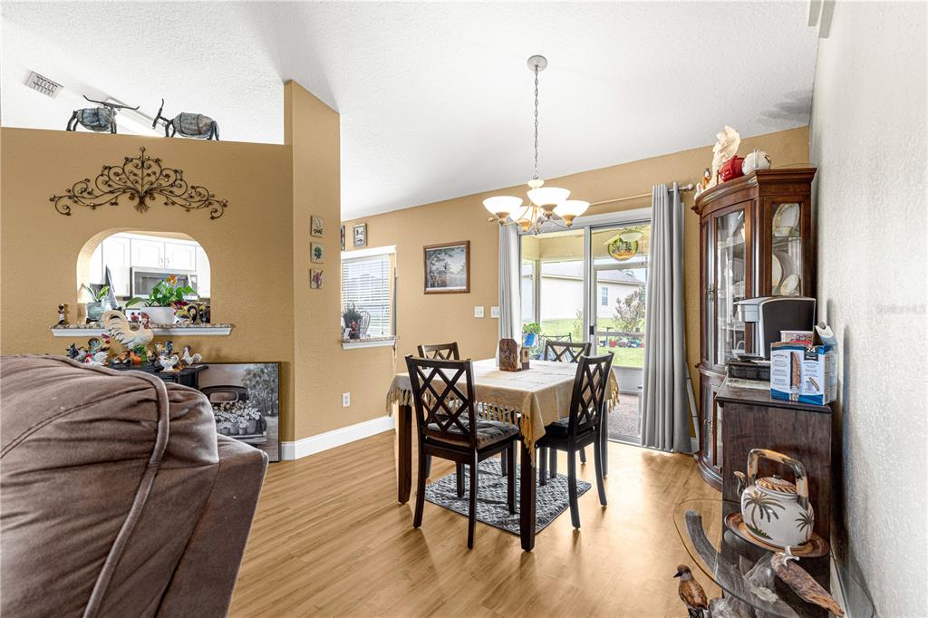 12459 Southeast 176th Loop Summerfield, FL 34491 - Photo 7 of 34 a view of a dining room and livingroom with furniture wooden floor a chandelier