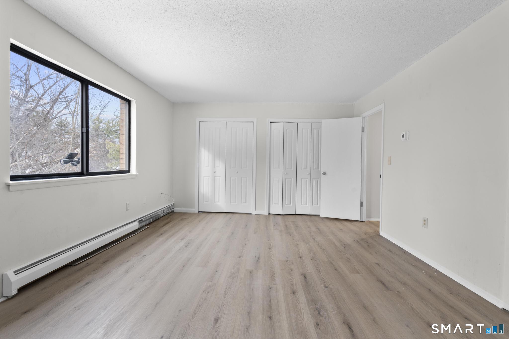 83 Sutton Place, Unit 83 Bloomfield, CT 06002 - Photo 19 of 29 a view of an empty room with a window and wooden floor