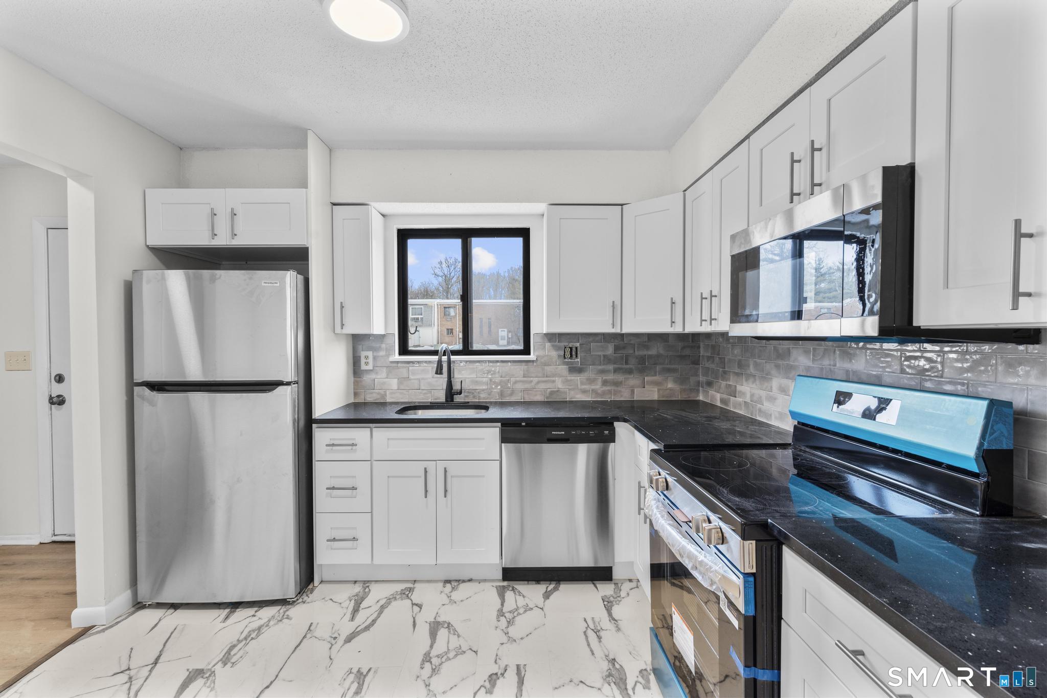 83 Sutton Place, Unit 83 Bloomfield, CT 06002 - Photo 5 of 29 a kitchen with stainless steel appliances granite countertop a refrigerator a stove a sink and white cabinets