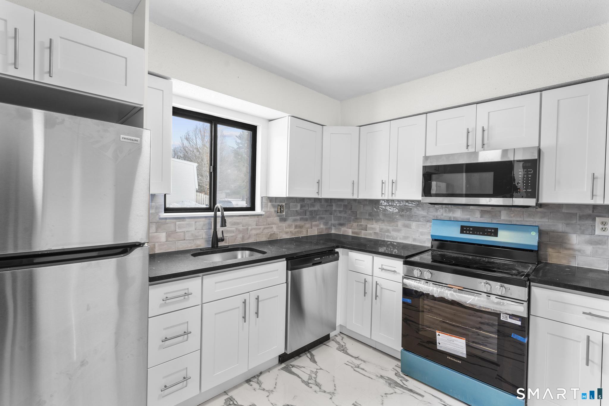 83 Sutton Place, Unit 83 Bloomfield, CT 06002 - Photo 6 of 29 a kitchen with white cabinets and stainless steel appliances