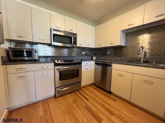 a kitchen with granite countertop a sink cabinets and stainless steel appliances
