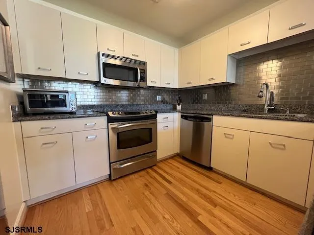 a kitchen with granite countertop white cabinets stainless steel appliances and sink