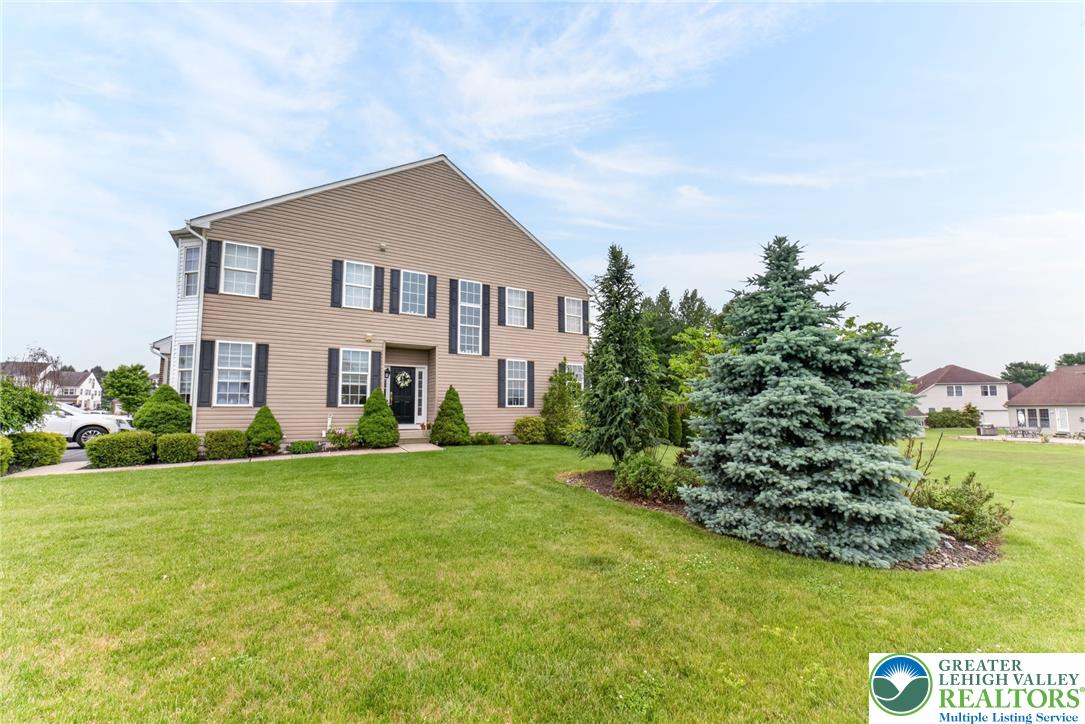 5440 Spring Ridge Drive West Macungie, PA 18062 - Photo 2 of 40 A classic two-story home with neutral siding, framed by manicured evergreens.
