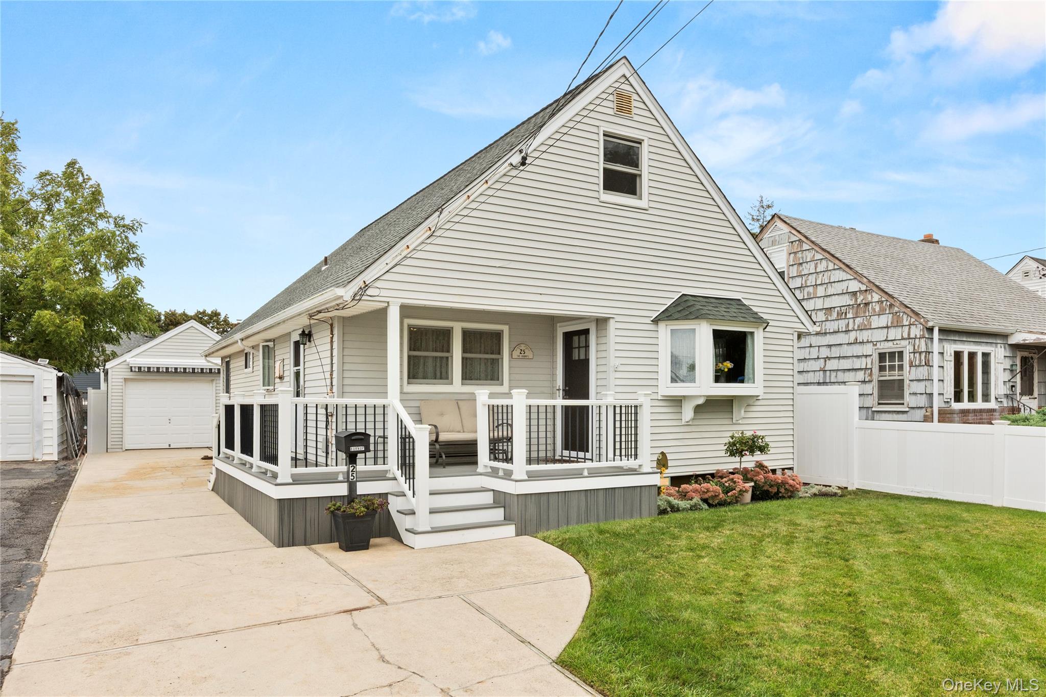 View of front of property with an outdoor structure, covered porch, a detached garage, and a shingled roof