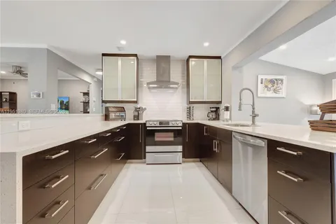 a large kitchen with stainless steel appliances kitchen island granite countertop a sink dishwasher a stove and white cabinets