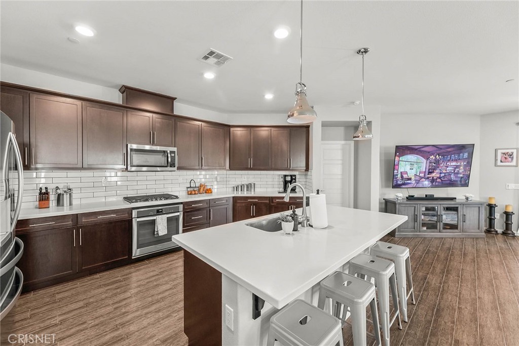 19663 Griffith Drive Saugus, CA 91350 - Photo 9 of 28 a large kitchen with stainless steel appliances kitchen island granite countertop a sink a stove a dining table and chairs