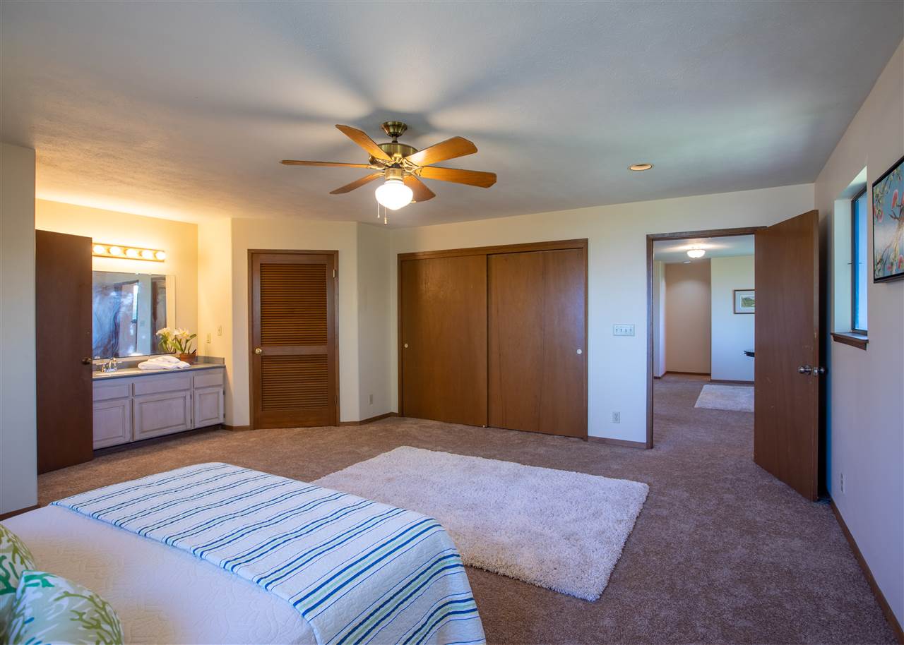586 Naalae Road Kula, HI 96790 - Photo 21 of 30 a bedroom with a bed and a chandelier