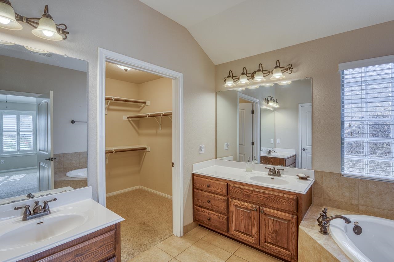 1403 Adam Burnet, TX 78611 - Photo 17 of 30 a bathroom with a sink double vanity granite tub shower and a mirror