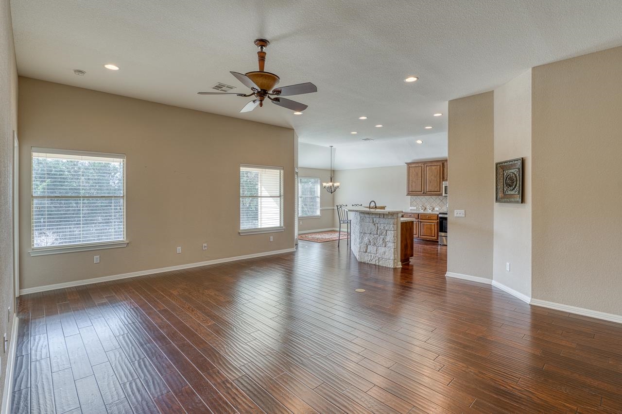 1403 Adam Burnet, TX 78611 - Photo 8 of 30 a view of an empty room with a kitchen and wooden floor