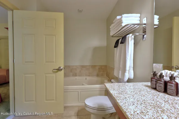 a bathroom with a granite countertop bathtub sink vanity mirror and toilet