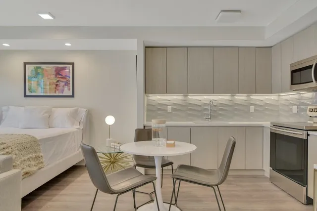 a kitchen with stainless steel appliances granite countertop a table chairs sink and cabinets