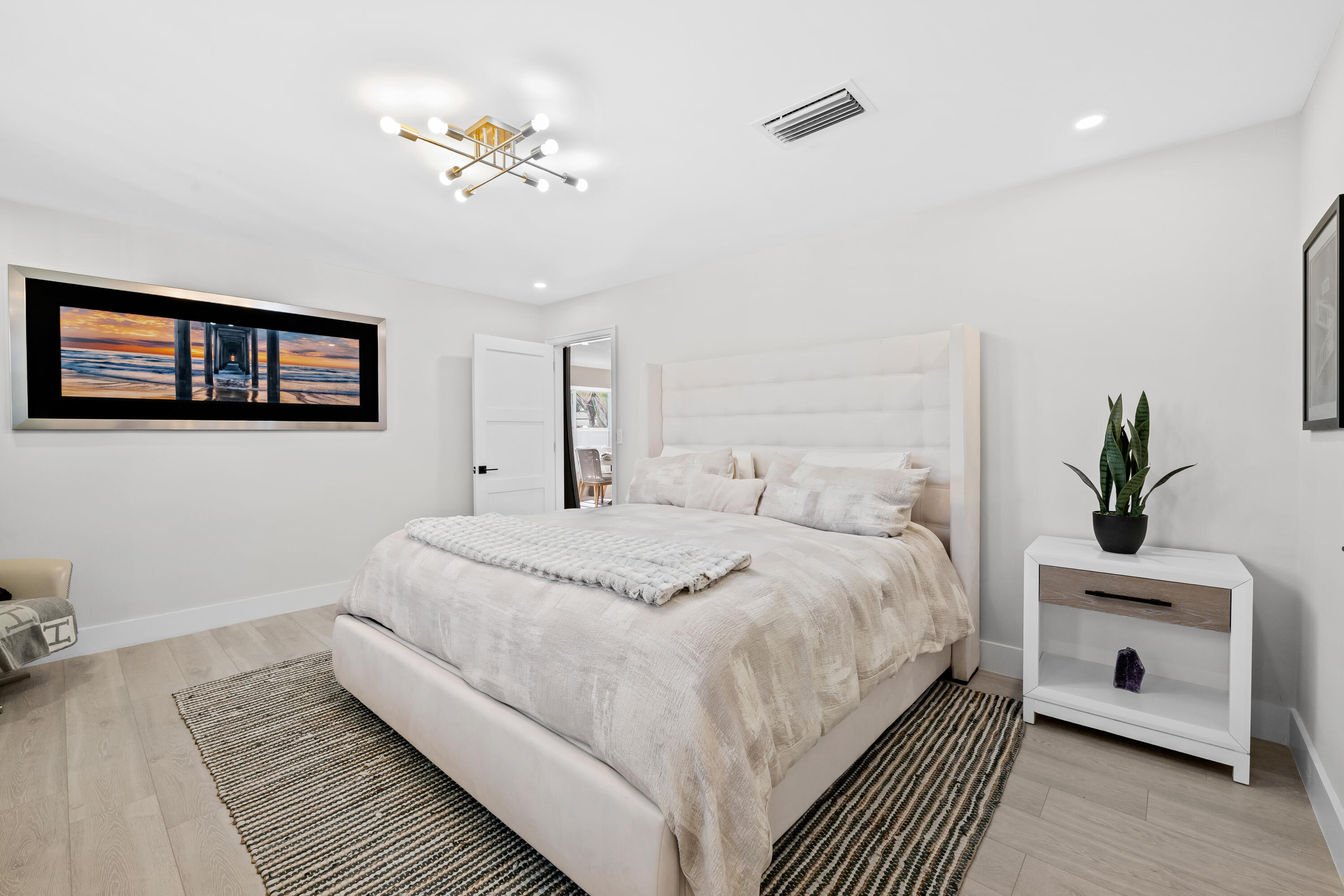 698 West Camino Boca Raton, FL 33486 - Photo 13 of 30 a spacious bedroom with a bed a chandelier and a potted plant