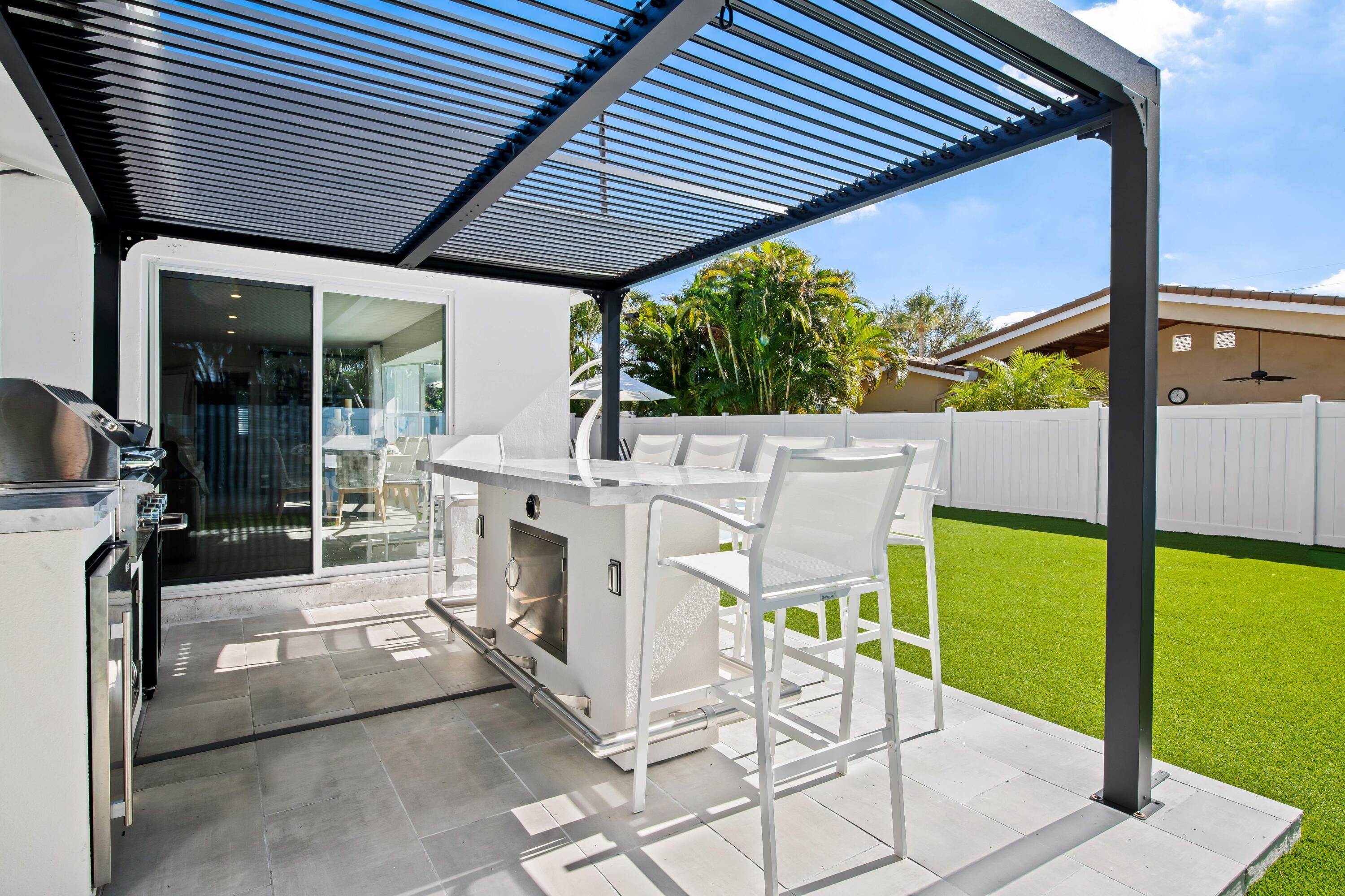 698 West Camino Boca Raton, FL 33486 - Photo 26 of 30 a view of an outdoor kitchen with a table and chairs