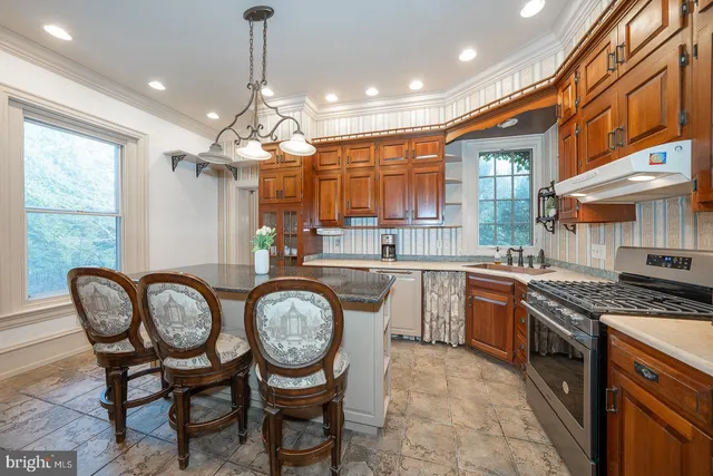 a kitchen with granite countertop a sink a stove and chairs