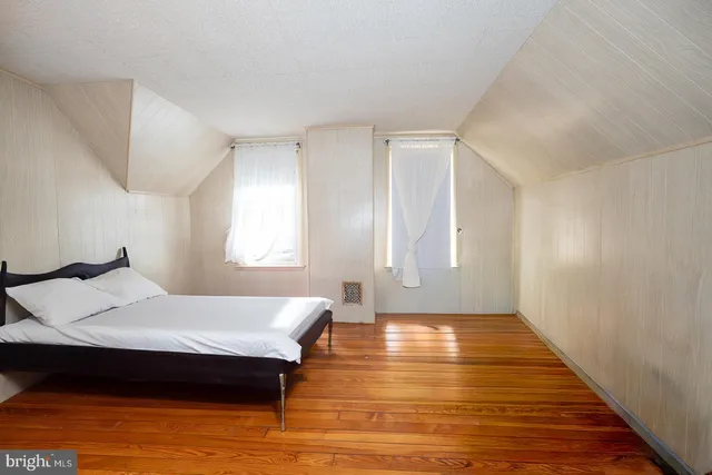 a spacious bedroom with a bed and wooden floor
