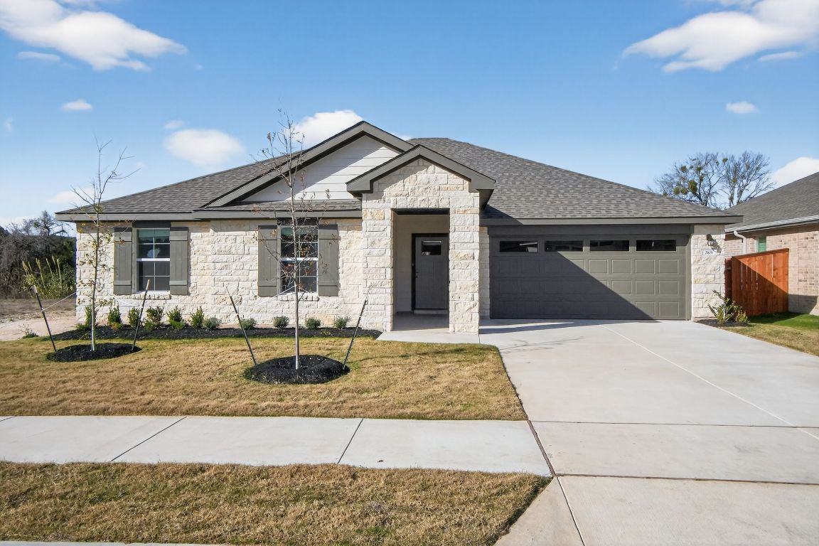 View of front of home featuring stone siding, concrete driveway, a shingled roof, and a garage