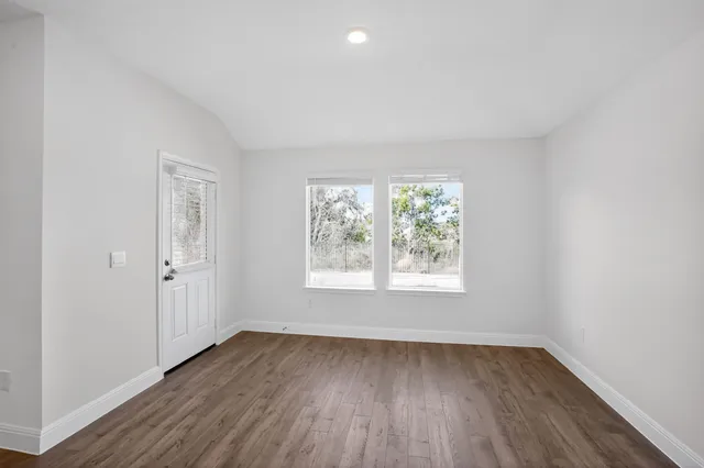 an empty room with wooden floor and window