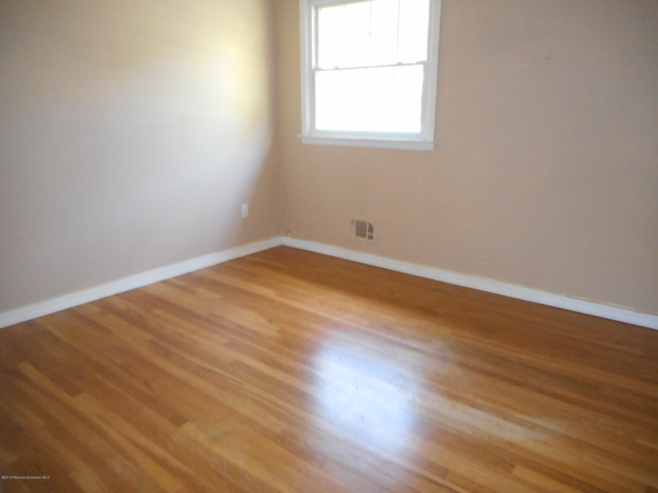 104 Bar Harbor Road Freehold, NJ 07728 - Photo 5 of 18 an empty room with wooden floor and windows