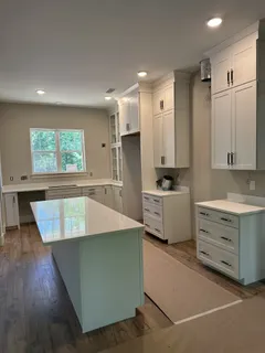 a large kitchen with kitchen island a sink a stove a refrigerator and white cabinets with wooden floor