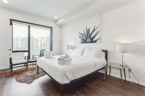 a bedroom with a bed a couch and a large window