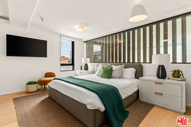 a bedroom with bed table and a flat screen tv