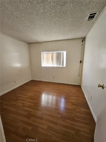 a view of an empty room with wooden floor and a hallway
