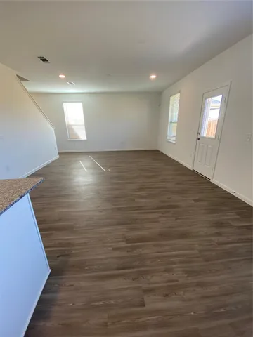 a view of an empty room with window and wooden floor