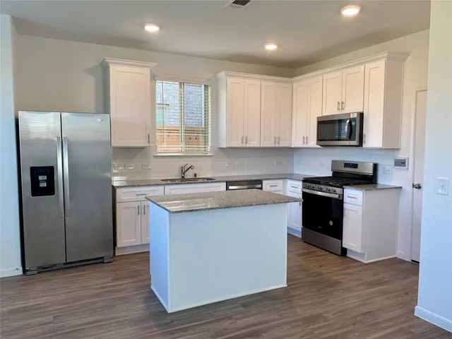 a kitchen with granite countertop a refrigerator and a stove top oven