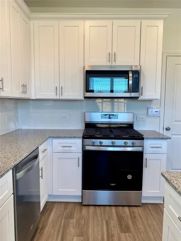 a kitchen with stainless steel appliances granite countertop a stove and a white cabinets