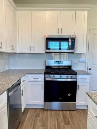 a kitchen with stainless steel appliances granite countertop a stove and a white cabinets