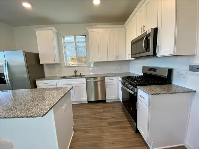 a kitchen with stainless steel appliances granite countertop a sink stove microwave and refrigerator