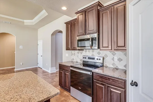 a kitchen with stainless steel appliances granite countertop a stove a sink and a microwave