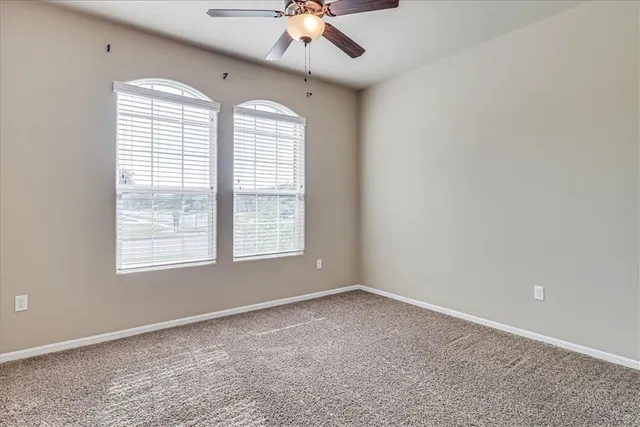 an empty room with a window and a fan