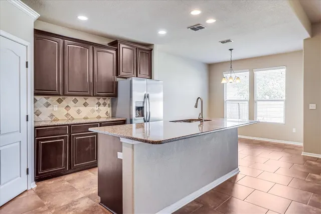 a kitchen with kitchen island granite countertop a sink stove and refrigerator