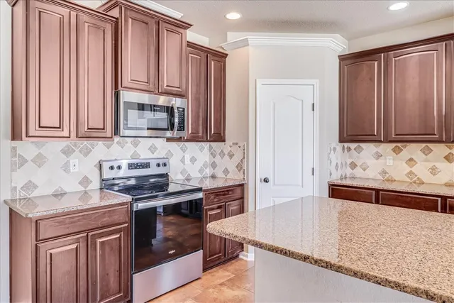 a kitchen with stainless steel appliances granite countertop a stove a sink and a microwave