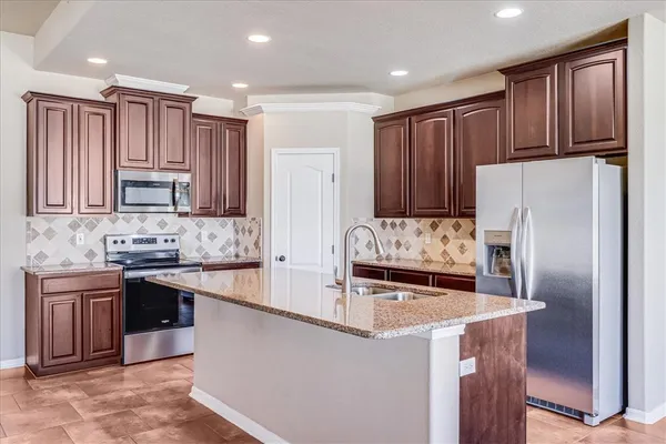 a kitchen with kitchen island granite countertop wooden cabinets a refrigerator and a sink