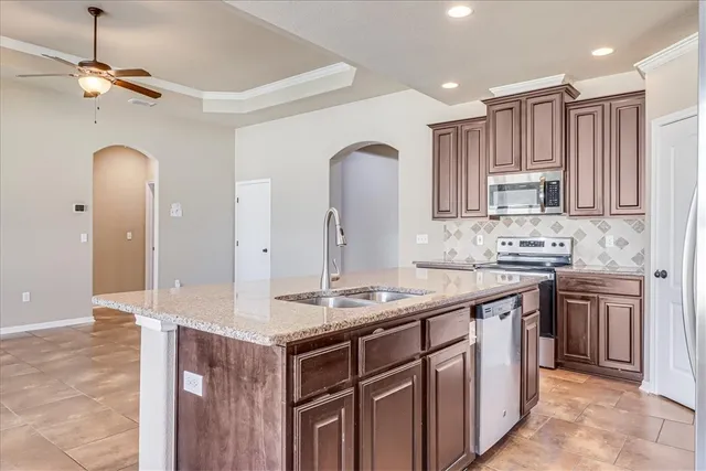 a kitchen with kitchen island granite countertop a sink stove and cabinets