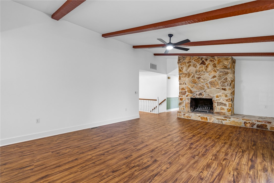 208 Williamsburg Road Anderson, SC 29621 - Photo 12 of 48 Rich wood floors anchor this open space beneath exposed ceiling beams and a stone fireplace.