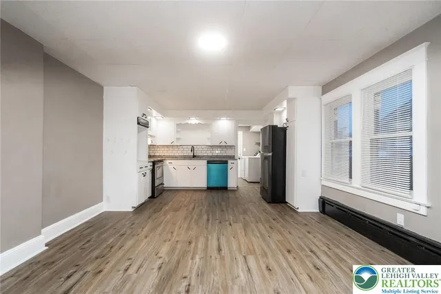 a kitchen with stainless steel appliances granite countertop a refrigerator a sink dishwasher and a oven with wooden floor