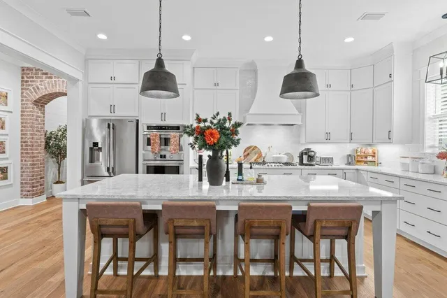 a kitchen with stainless steel appliances granite countertop a kitchen island and chairs in it
