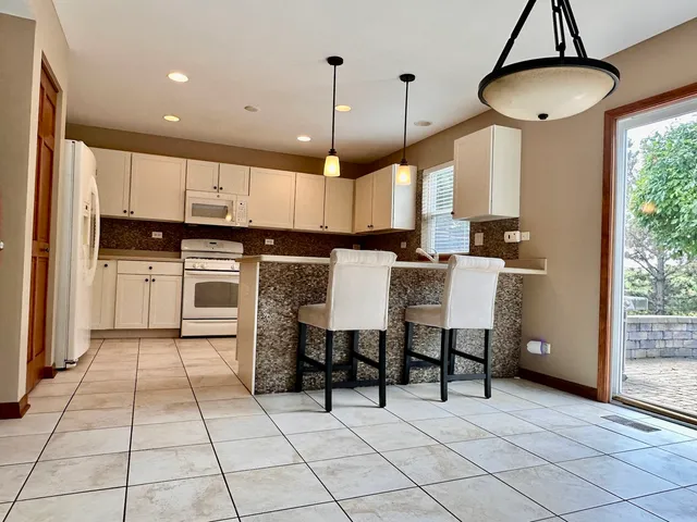 a kitchen with stainless steel appliances a stove a refrigerator and chairs