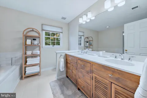 a spacious bathroom with a double vanity sink a large mirror and a