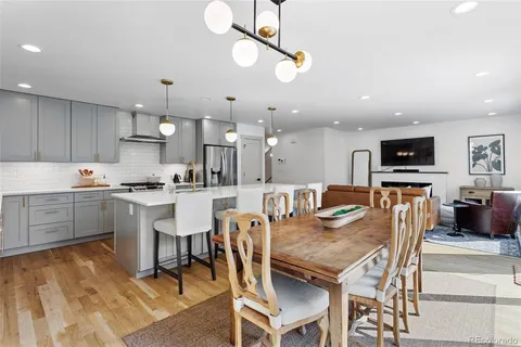 a kitchen with stainless steel appliances kitchen island granite countertop a table chairs and a refrigerator
